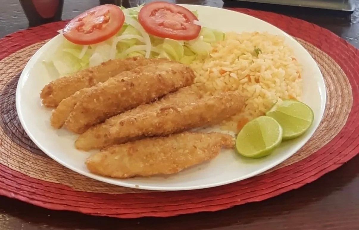 Filete de pescado empanizado con arroz, ensalada y limones