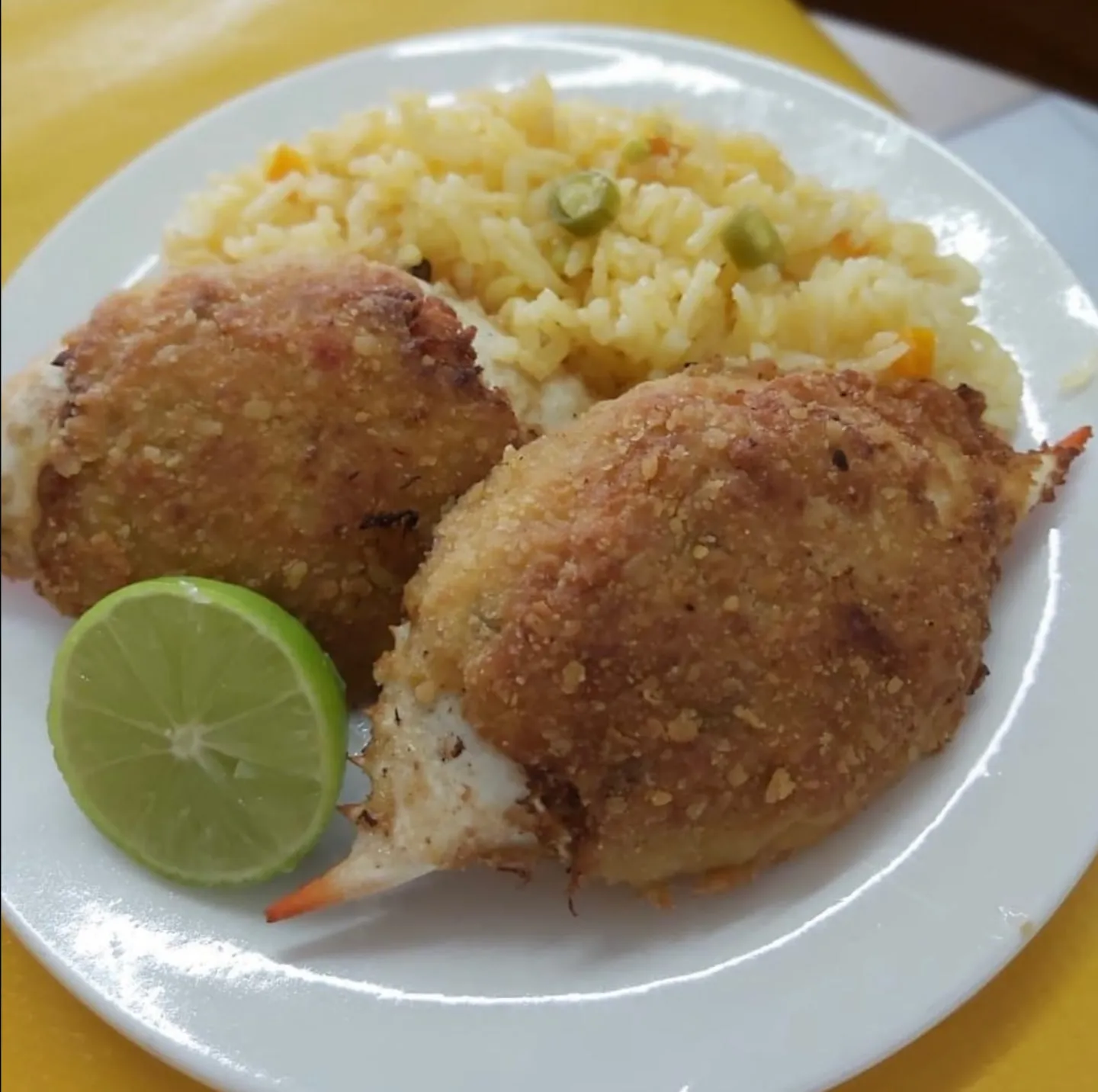 Dos jaibas rellenas empanizadas con arroz amarillo y limón